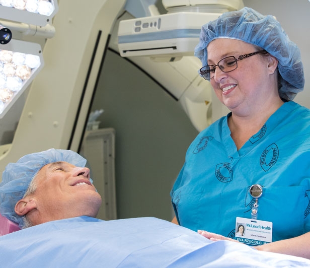 A man smiling at a nurse during preparations for a vascular surgical procedure