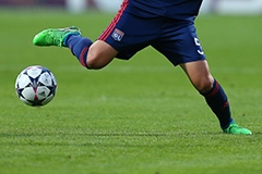A soccer player wearing a blue uniform winding up to kick a soccer ball