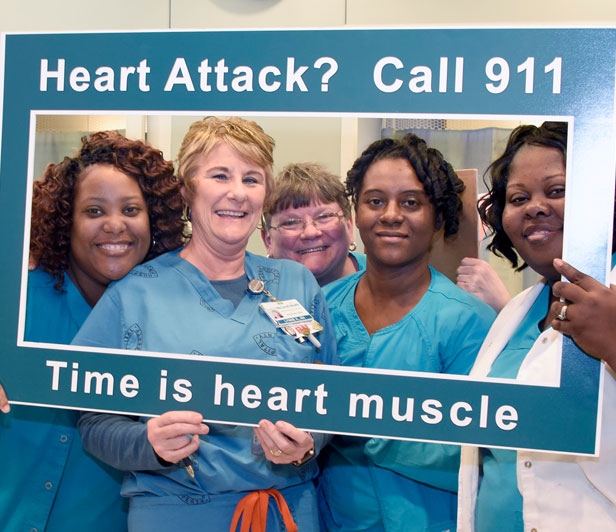 McLeod Health cardiatric nurses holding a sign encouraging people to call 911 at the first sign of a heart attack