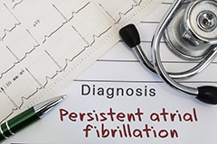 An EKG, stethoscope and a doctor's diagnosis note reading: persistent arterial fibrillation