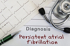 An EKG, stethoscope and a doctor's diagnosis note reading: persistent arterial fibrillation