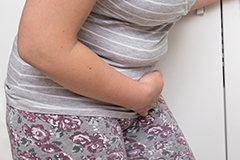 A woman hunched over, clutching her lower stomach in pain