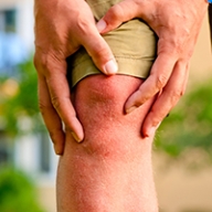 A man wearing shorts with both hands wrapped around his knee