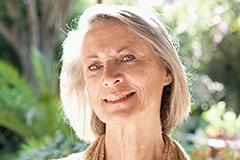 An older white woman with silver hair smiling at the camera