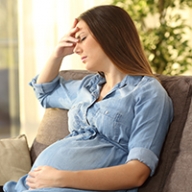 A pregnant woman holding her head in pain