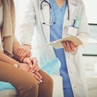 A doctor holding a female patient's wrist as she reads a chat