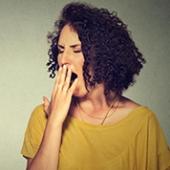 A tired woman covering her mouth while yawning