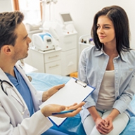 A doctor with a clip board talking to a female patient