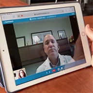 A doctor talking with a patient via a tablet device