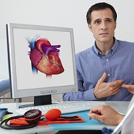 A patient talking to a doctor while a heart diagram is on a computer screen