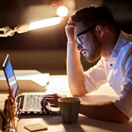 A man working at his computer in dim lighting