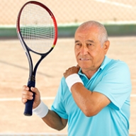 An older man grabbing his shoulder with discomfort while playing tennis