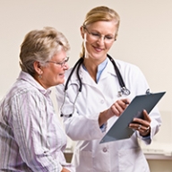 A female doctor showing a clipboard while talking to an older female patient