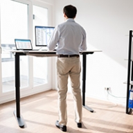 A man using a standing desk in a bright room